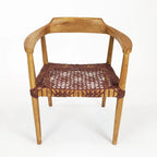 Poltrona da salotto con braccioli in legno di teak e seduta in pelle intrecciata