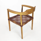 Poltrona da salotto con braccioli in legno di teak e seduta in pelle intrecciata